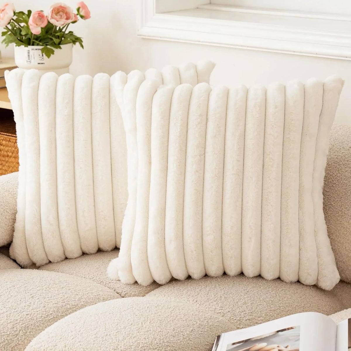 A cream colored square faux rabbit fur cushion cover displayed on a beige sofa.