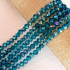 A strand of faceted blue-green glass beads is laid across a beige woven fabric.