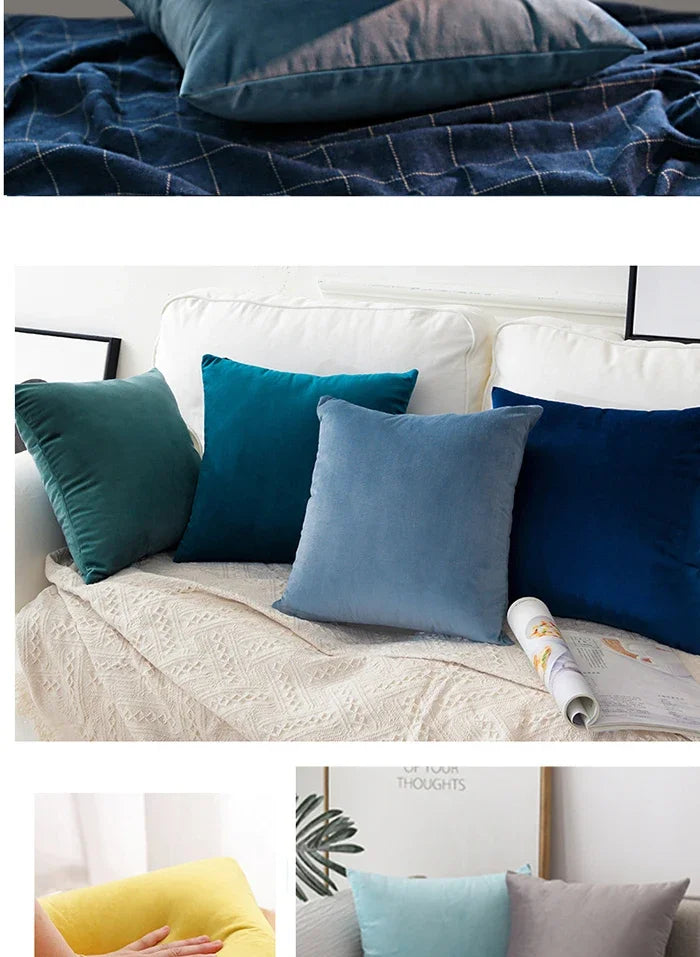 A collection of velvet throw pillows in shades of teal, blue, and gray on a white sofa.
