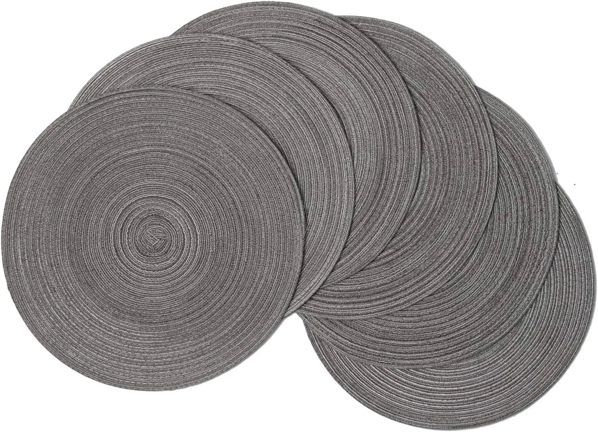 A stack of six round, gray braided placemats for dining and party decor.