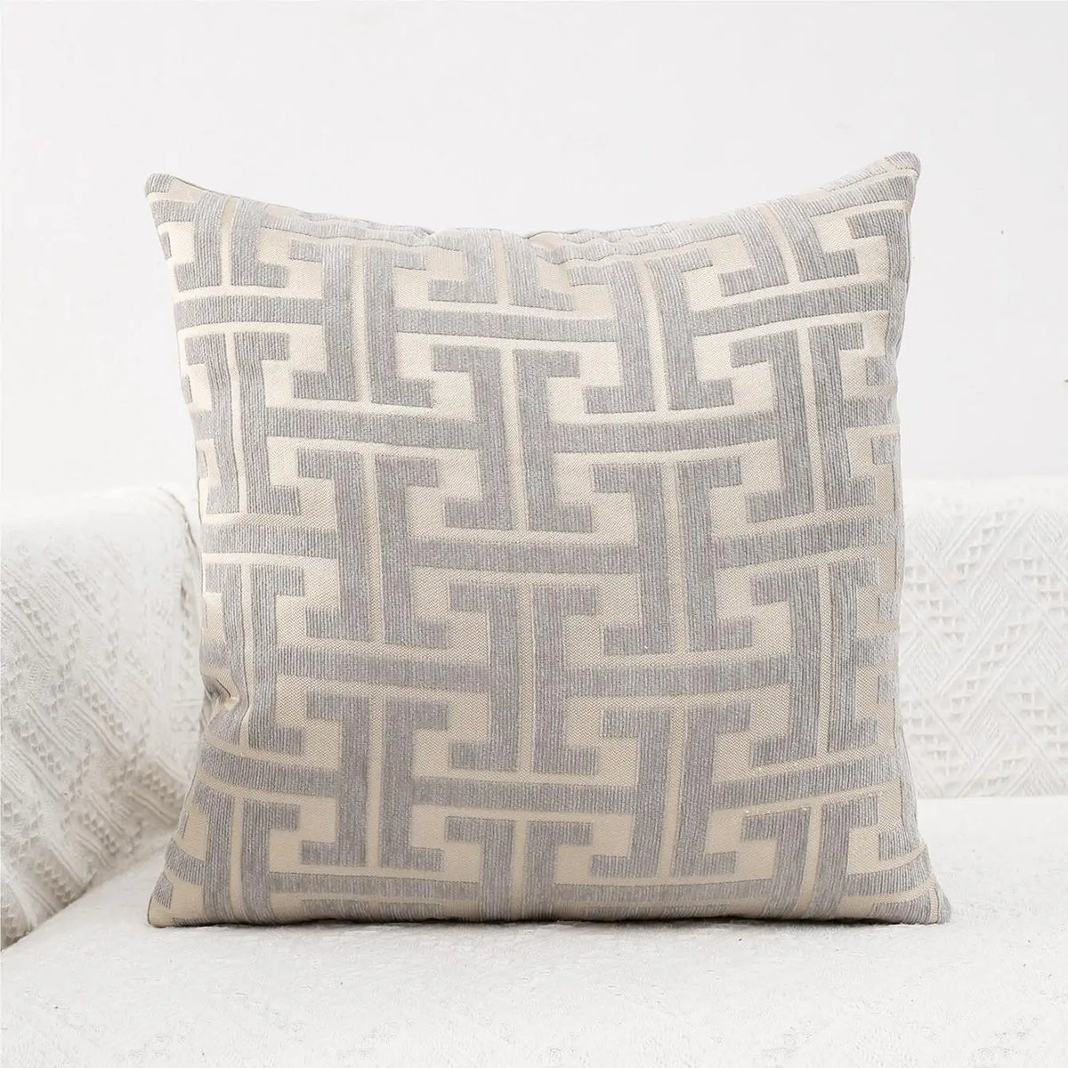 A square lumbar pillow cover with a light gray and beige geometric maze pattern.