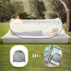 Portable mosquito net pop-up bed set up on the ground with a person relaxing under it.