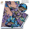A bolt of grand wax print fabric featuring vibrant purple, blue, and gold floral patterns on a light pink background.