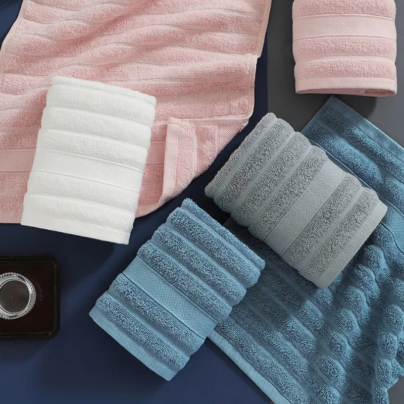 A set of four textured face towels in pink, white, and blue tones are displayed on a dark surface.