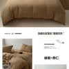 A beige soft 100% cotton duvet cover set displayed on a bed with pillows and a small wooden table.