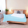 Light blue high-stretch elastic box spring cover displayed on a wooden bed frame with fluffy pillows.