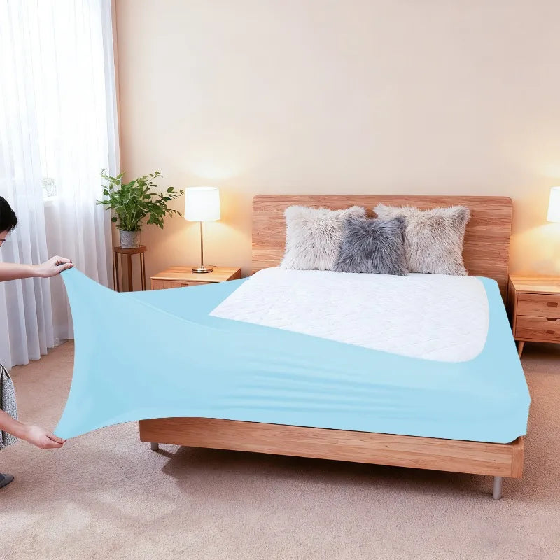 Light blue high-stretch elastic box spring cover displayed on a wooden bed frame with fluffy pillows.