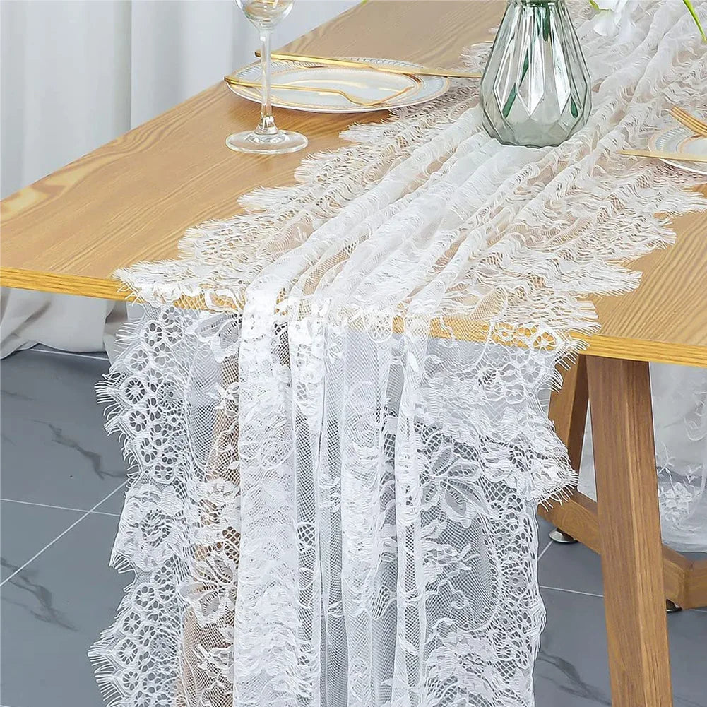 White embroidered floral lace table runner draped over a wooden table.
