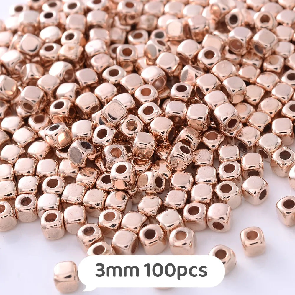 A pile of small rose gold colored geometric acrylic beads for jewelry making