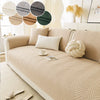 A beige anti-slip fabric sofa cushion cover displayed on a light-colored sofa with decorative pillows and natural accents.