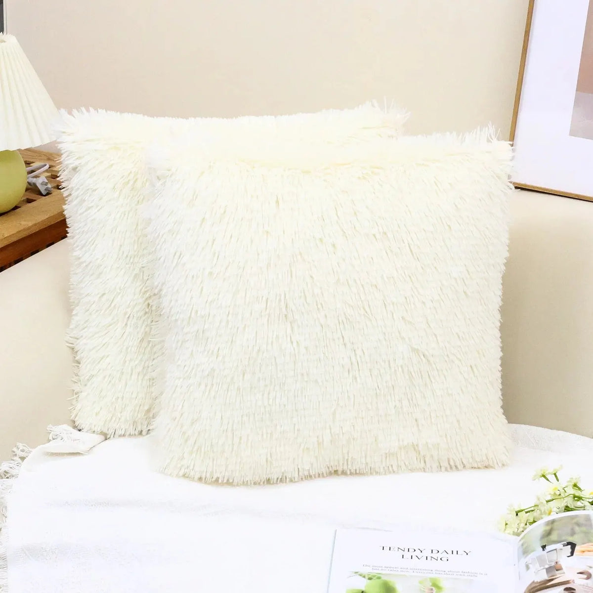A fluffy white faux fur throw pillow resting on a white surface.