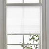 White pleated blackout curtains covering a window pane.