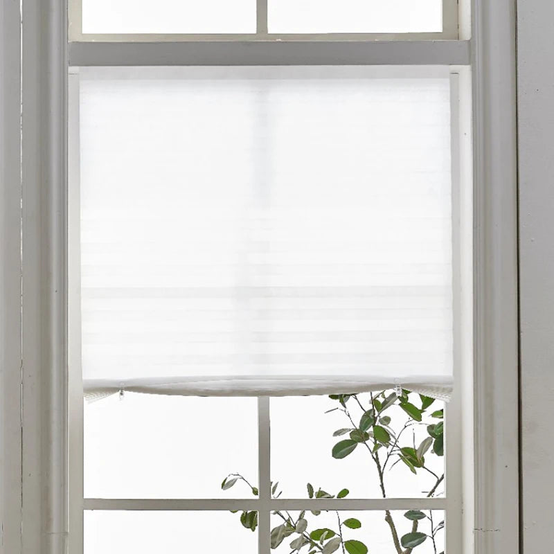 White pleated blackout curtains covering a window pane.