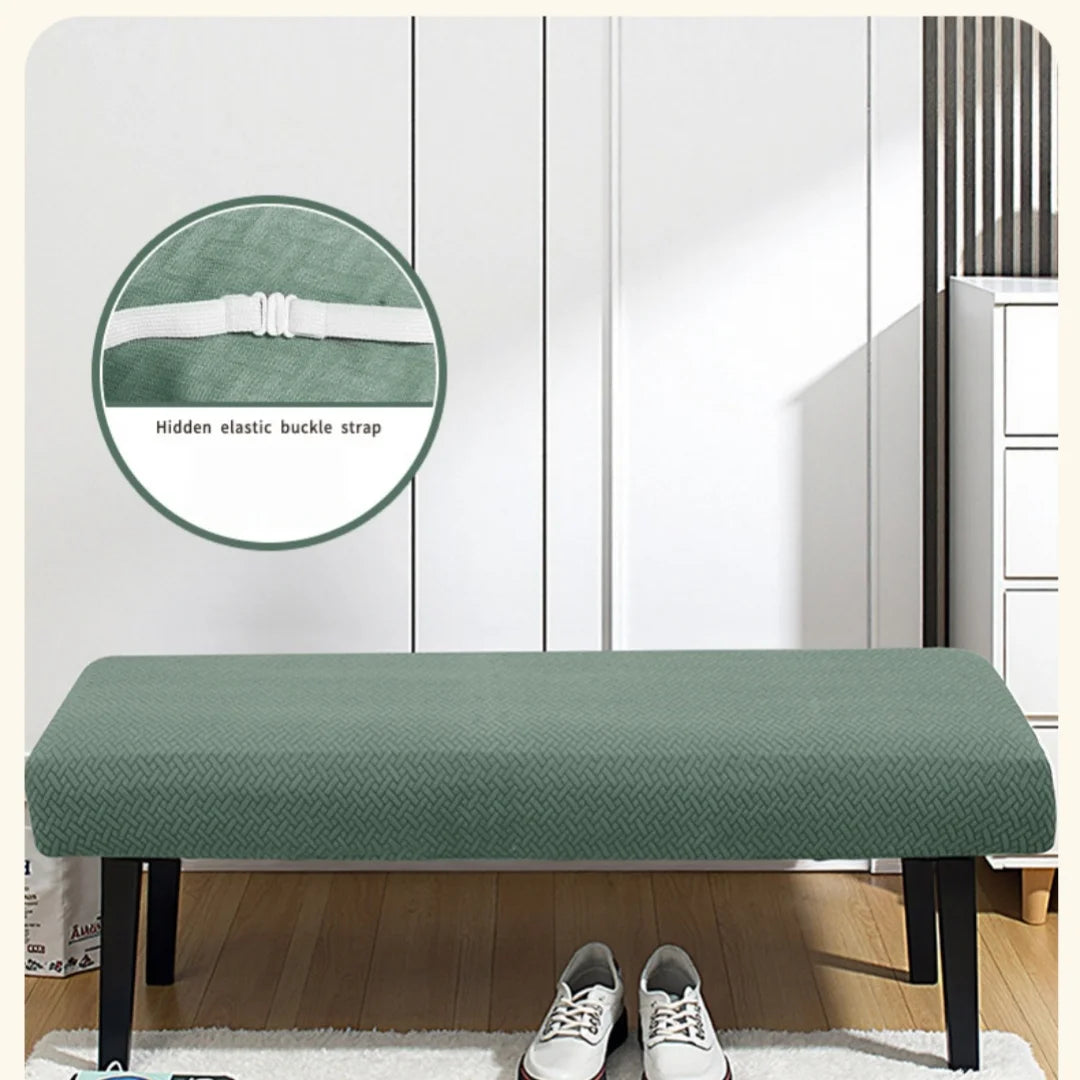 A green stretch jacquard dining bench cover placed on a wooden table with white shoes nearby.