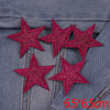 Five pink glitter star patches embroidered on a denim fabric.
