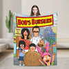 A person holding a large throw blanket featuring characters from Bob's Burgers and other cartoon figures.