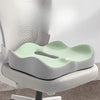 A light green ergonomic memory foam seat cushion placed on a gray office chair.