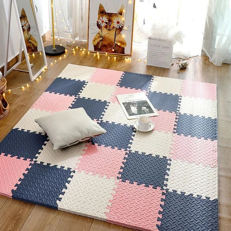 A pink, white, and navy checkered foam play mat for babies and toddlers placed on a wooden floor.