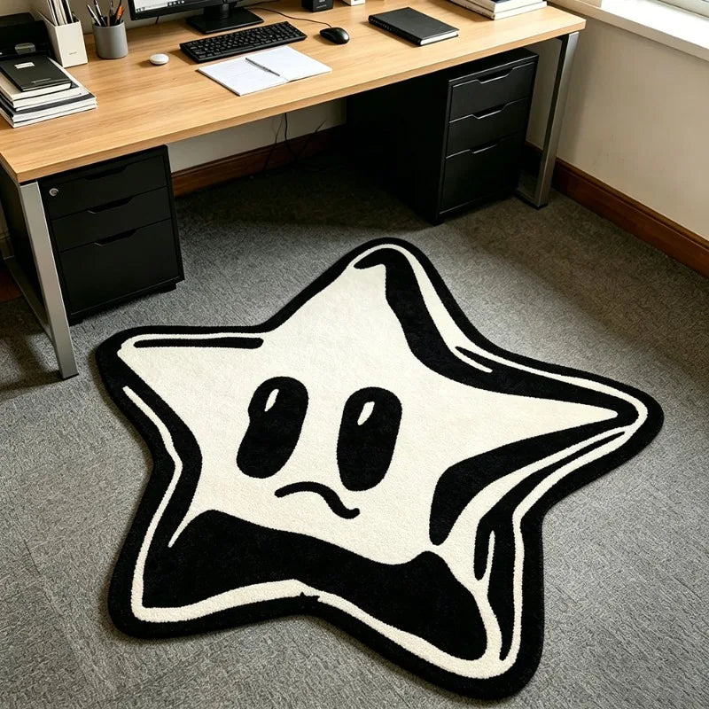 A black and white decorative pentagram rug with a simple, slightly sad face design on a gray carpet.