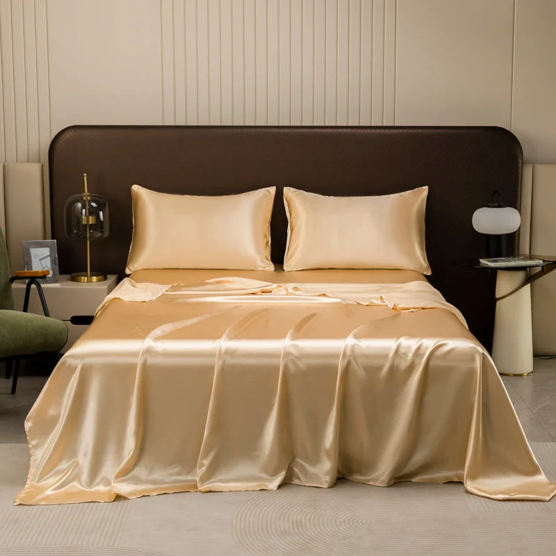 A luxurious satin flat bed sheet set in a golden beige color is displayed on a bed with a dark brown headboard.