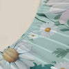 A close-up of a light mint green fitted mattress protector sheet with a white floral print featuring daisies and green leaves