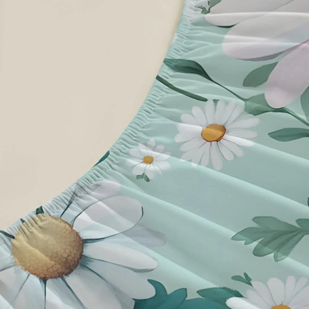 A close-up of a light mint green fitted mattress protector sheet with a white floral print featuring daisies and green leaves