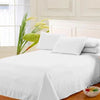 White premium flat bed sheet draped on a bed with a light-colored headboard and natural greenery.