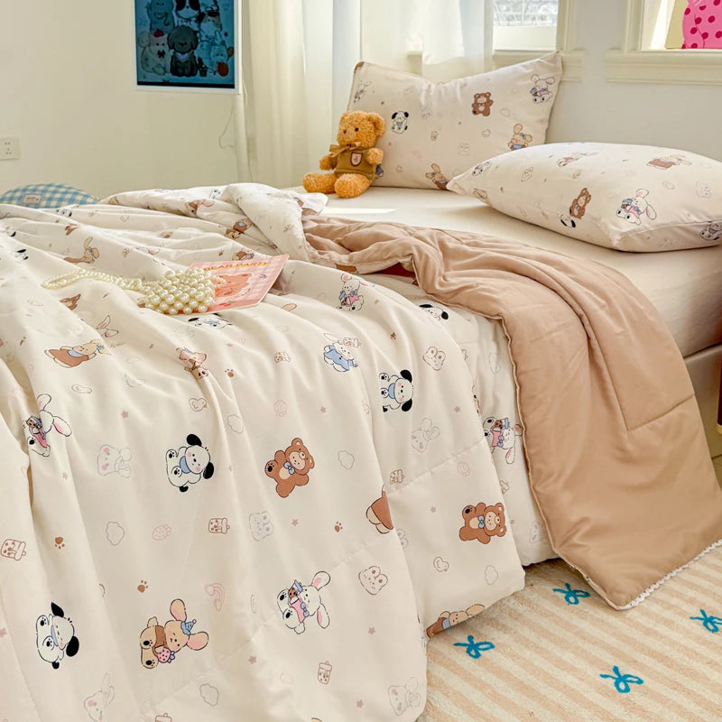 A light pink quilted blanket with a white pattern is displayed on a bed, next to pillows and a window.
