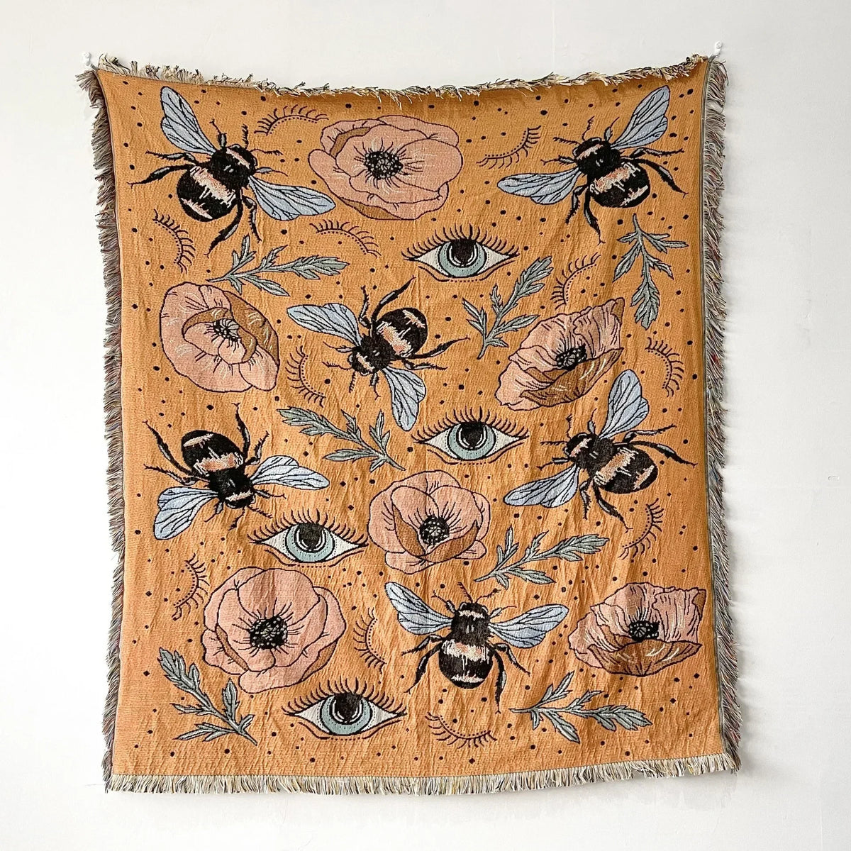 A bohemian geometric throw blanket featuring a pattern of bees and floral elements in earthy tones.