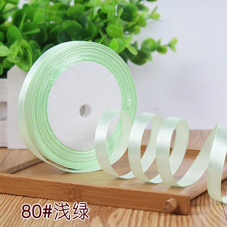 Roll of light green satin ribbon used for crafting or decoration
