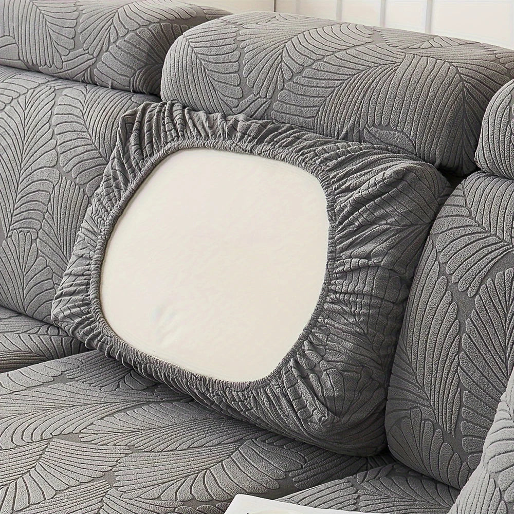 A gray sofa slipcover featuring a textured leaf pattern and a central white cushion.