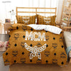 A yellow quilted duvet cover set featuring MCM embroidered motifs on a white background.