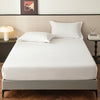 A clean white fitted sheet is laid on a bed, displayed in a modern bedroom setting.