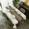 A long white rectangular table set with placemats and decorative fabric runners in earth tones.