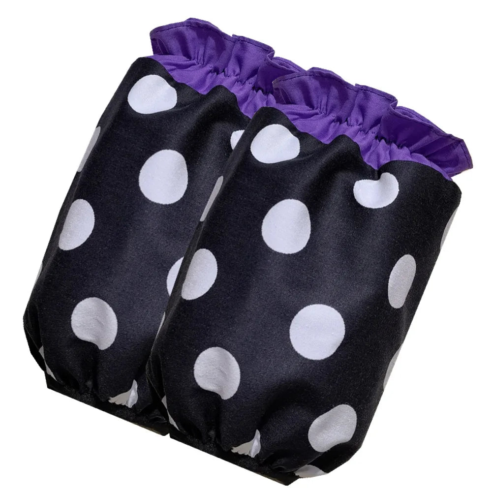 A black polka dot ruffle apron with purple trim and pockets.