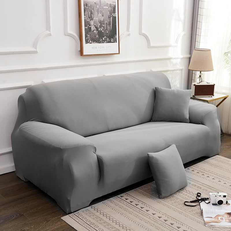 A modern gray faux silk sofa cover displayed indoors against a white wall with framed art.