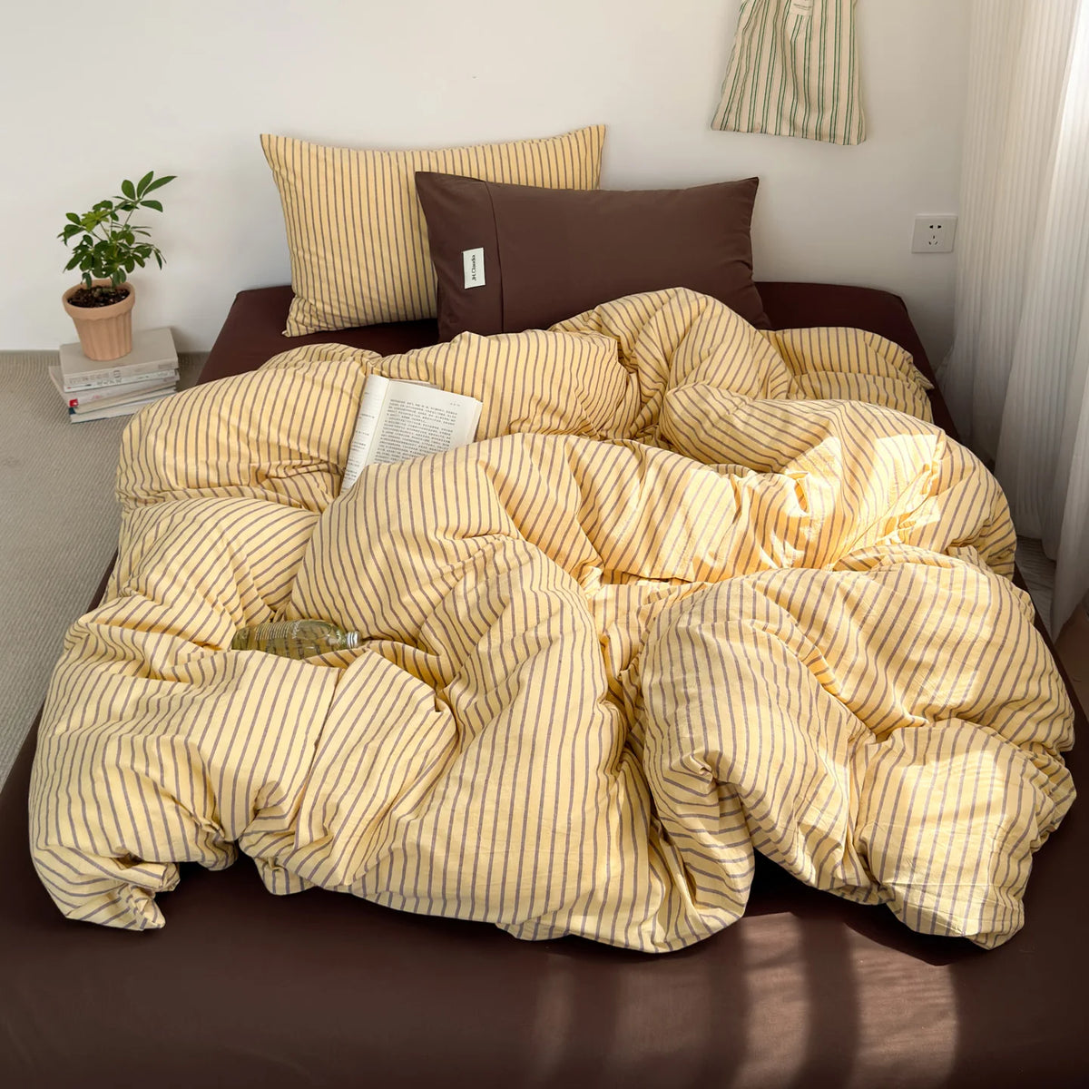 A yellow and beige striped cotton duvet cover set displayed on a bed with brown bedding.