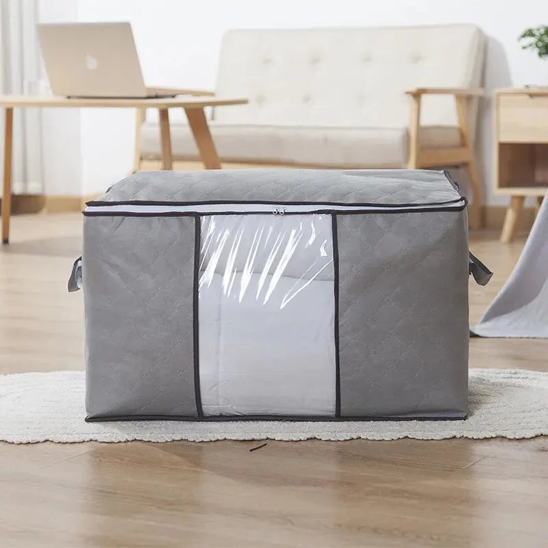 A gray portable quilt and clothing storage bag lying on a light-colored rug indoors.