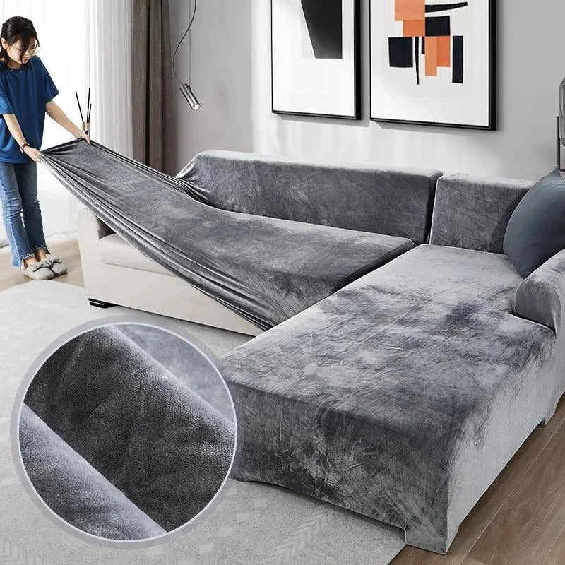 A person is draping a gray velvet sofa cover over an L-shaped sectional sofa.