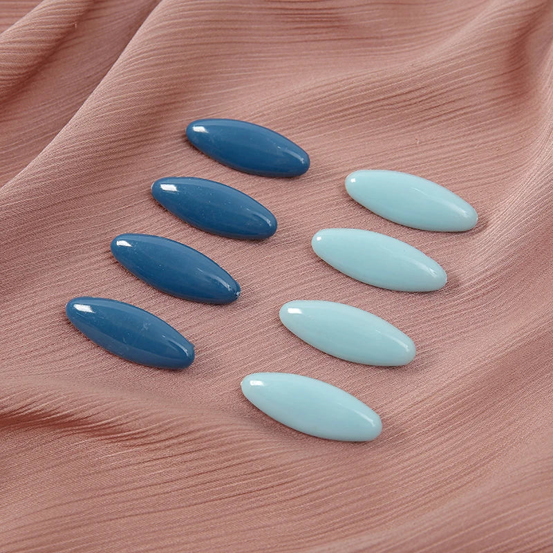 Eight plastic safety pins in varying shades of blue and light blue arranged on pink fabric.