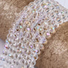 A close-up of clear faceted rondelle glass beads strung together on a gold textured surface.
