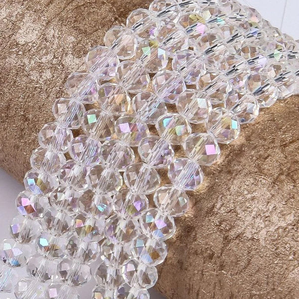 A close-up of clear faceted rondelle glass beads strung together on a gold textured surface.