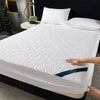 White quilted mattress protector with a blue accent lying on a bed.