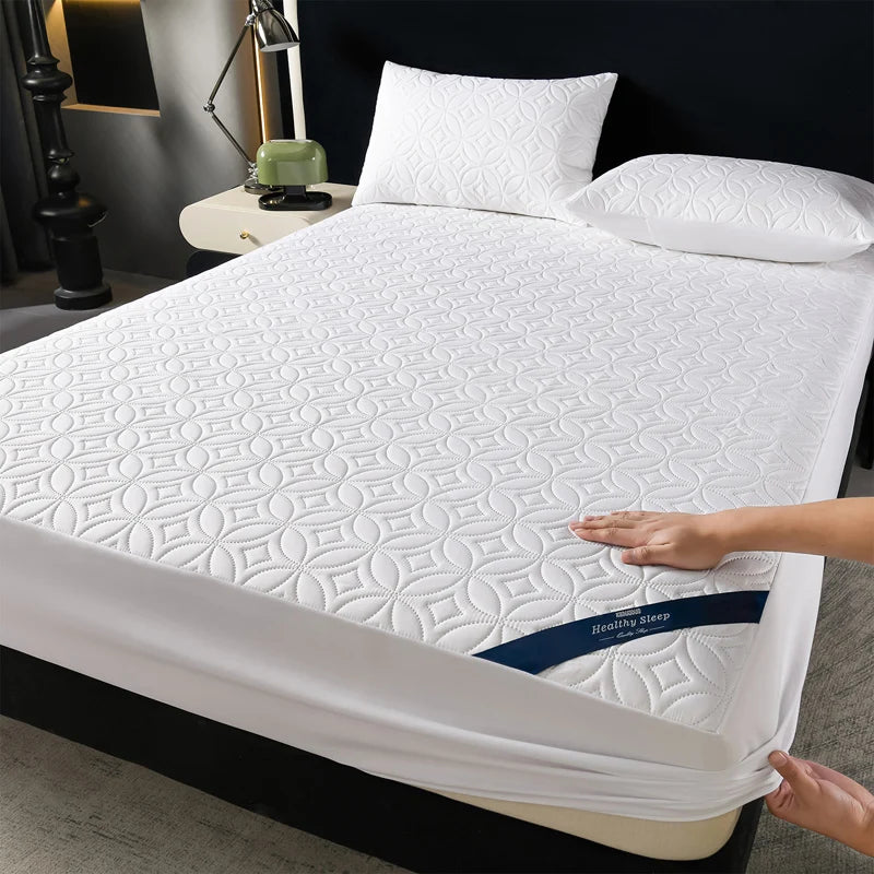 White quilted mattress protector with a blue accent lying on a bed.