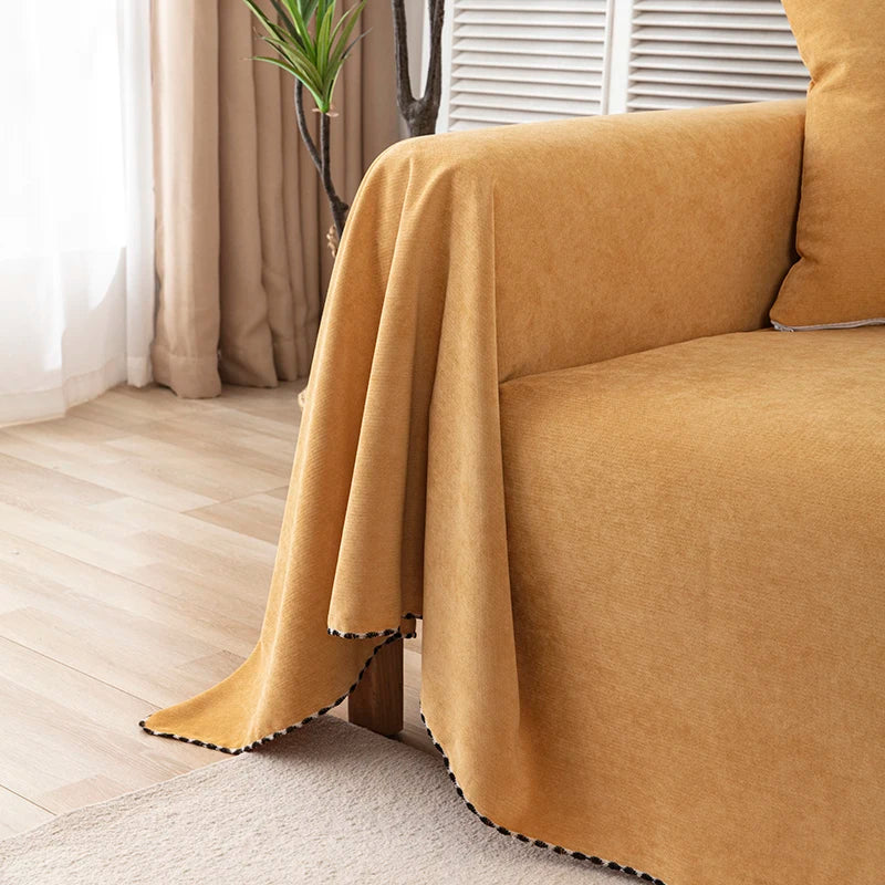 A mustard yellow waterproof sofa cover blanket draped over a couch in a bright room.
