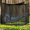 A person relaxing in a hammock suspended within a large black mosquito netting structure outdoors.