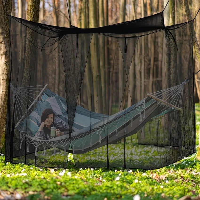 A person relaxing in a hammock suspended within a large black mosquito netting structure outdoors.