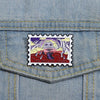 A vintage enamel lapel pin featuring a graphic design of a skull with purple and yellow hair against a red background.