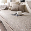 A beige linen sofa cover with neutral throw pillows and a white cup on the surface.