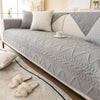 A light gray washed cotton sofa cover with a quilted texture and non-slip backing displayed on a sofa.